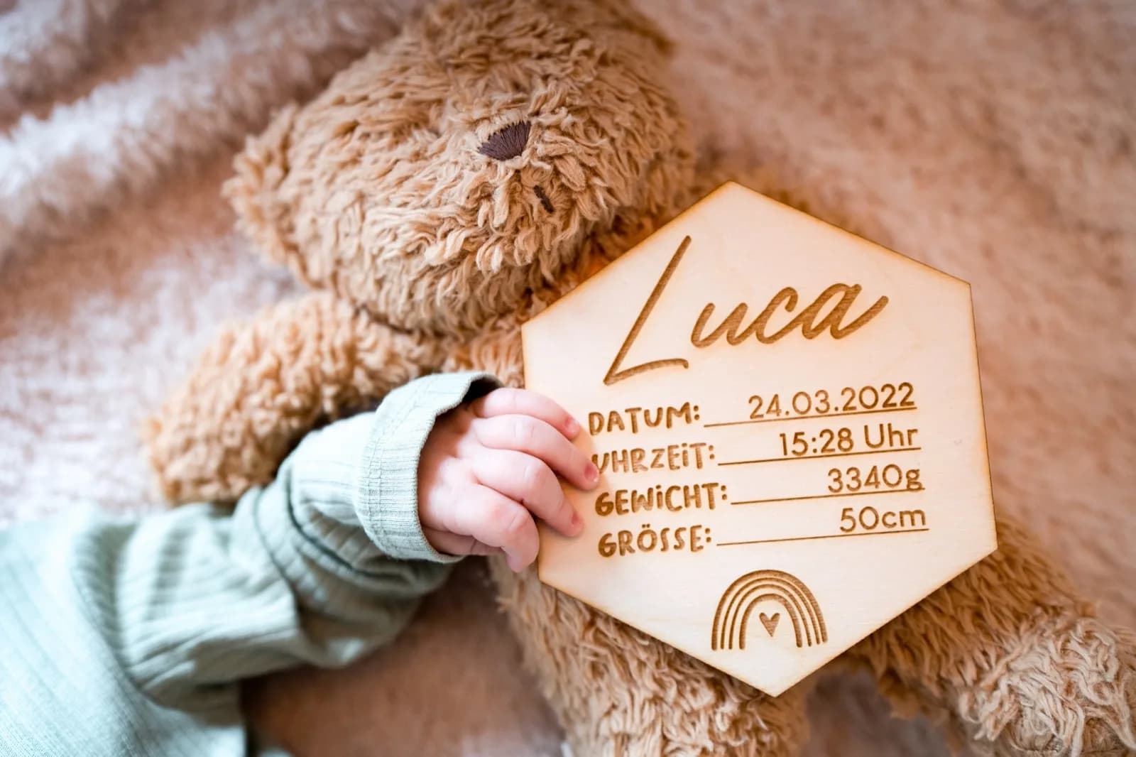 Personalisierte Geburtstafel aus Holz mit Lasergravur neben einem Neugeborenen als Taufgeschenk