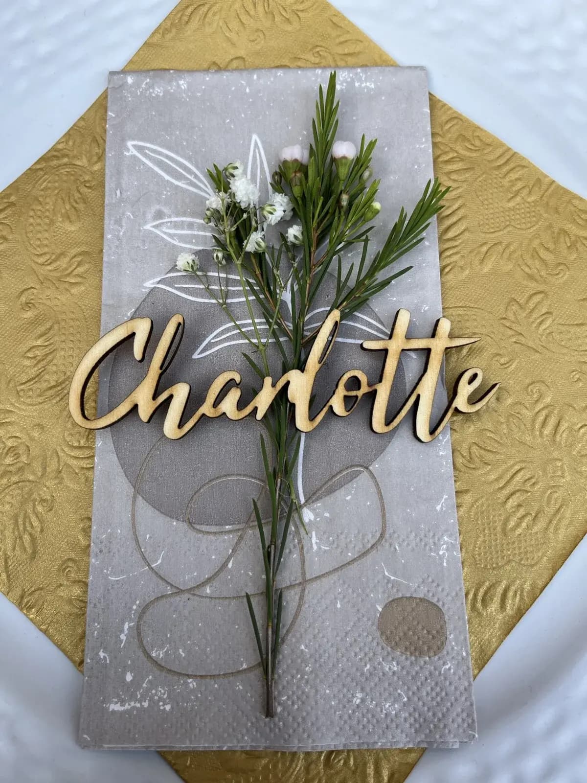 Lasergeschnittene Platzkarte aus Holz mit Namenszug auf einer Hochzeitstafel