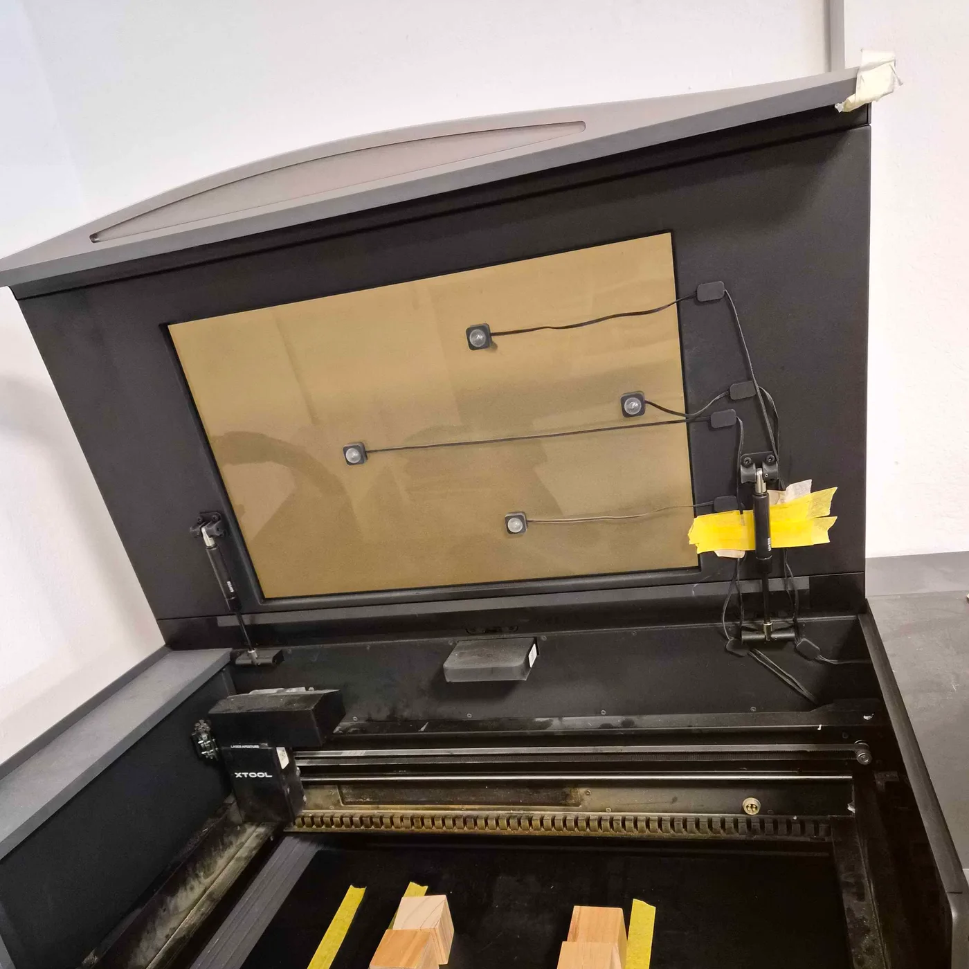 Geöffneter Lasercutter in der LaserFein-Werkstatt mit eingelegten Holzplatten